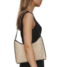 Woman holding a woven handbag against a plain background