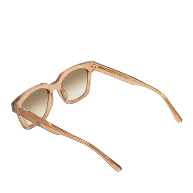 Sunglasses with gold frame and light-colored lenses on a white background