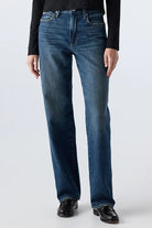 Person wearing a black long-sleeve shirt and blue jeans on a white background