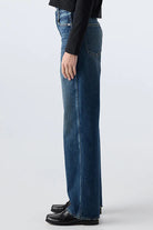 Person wearing a black top and blue jeans on a white background