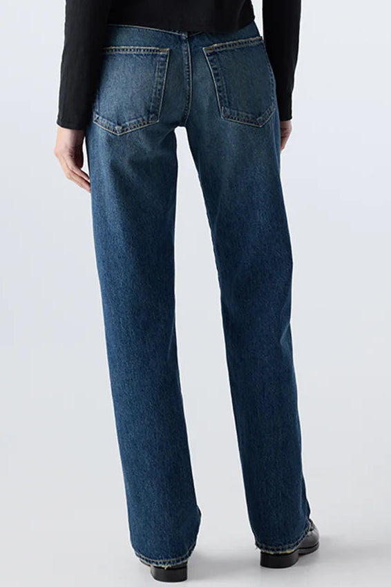 Person wearing a black long-sleeve shirt and blue jeans on a white background