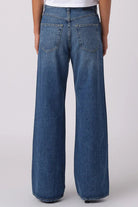 Person wearing a white t-shirt and blue jeans on a plain background