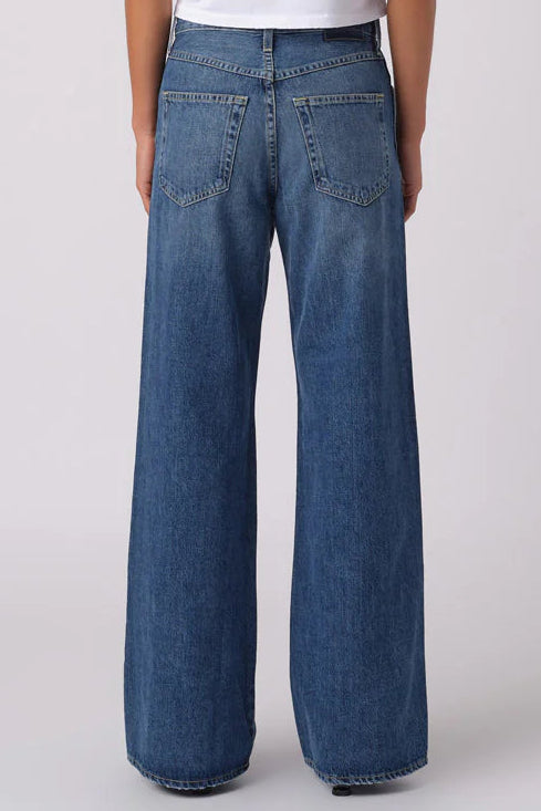 Person wearing a white t-shirt and blue jeans on a plain background