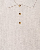 Close-up of a textured beige shirt with gold buttons.
