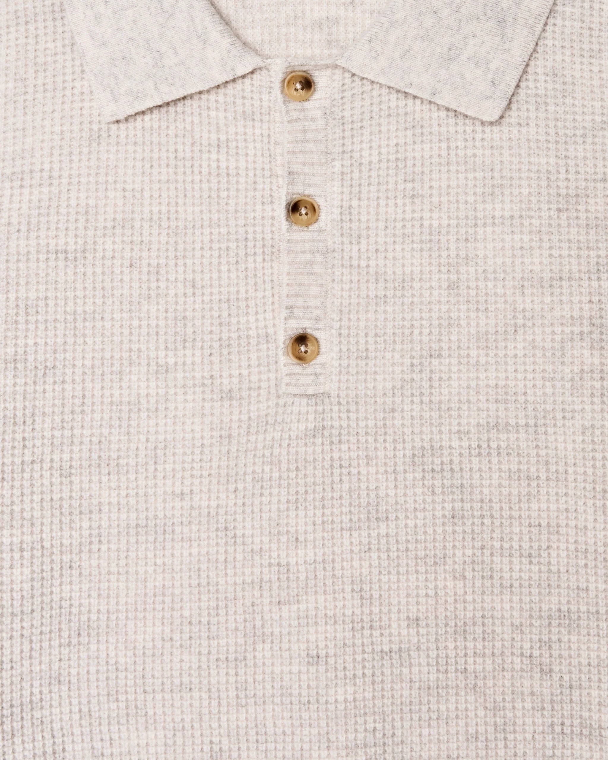 Close-up of a textured beige shirt with gold buttons.