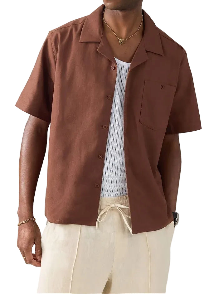 Man wearing a brown short-sleeve shirt and beige pants on a light gray background