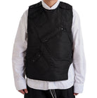 Person wearing a black quilted vest over a white shirt on a white background