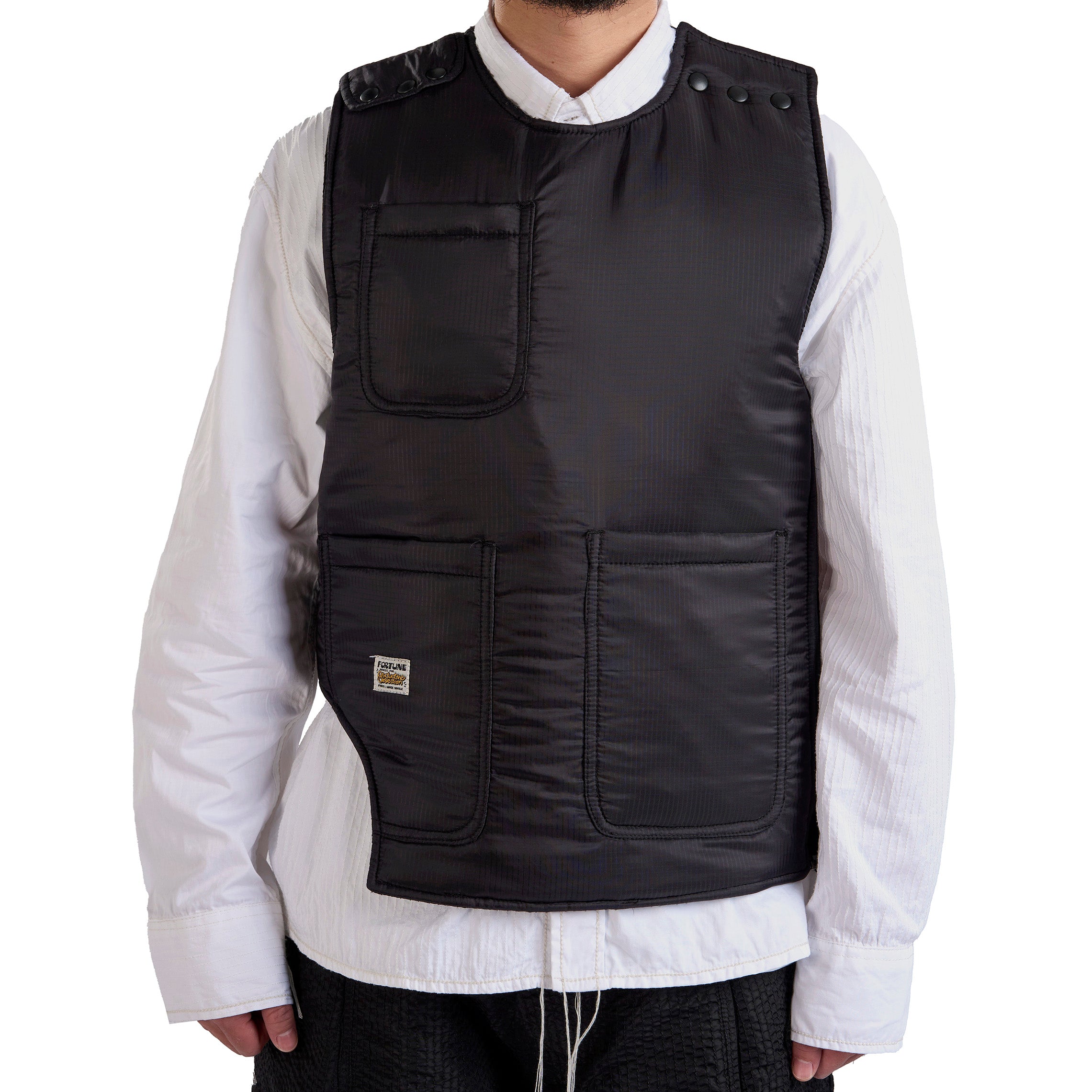 Person wearing a black vest over a white shirt on a white background