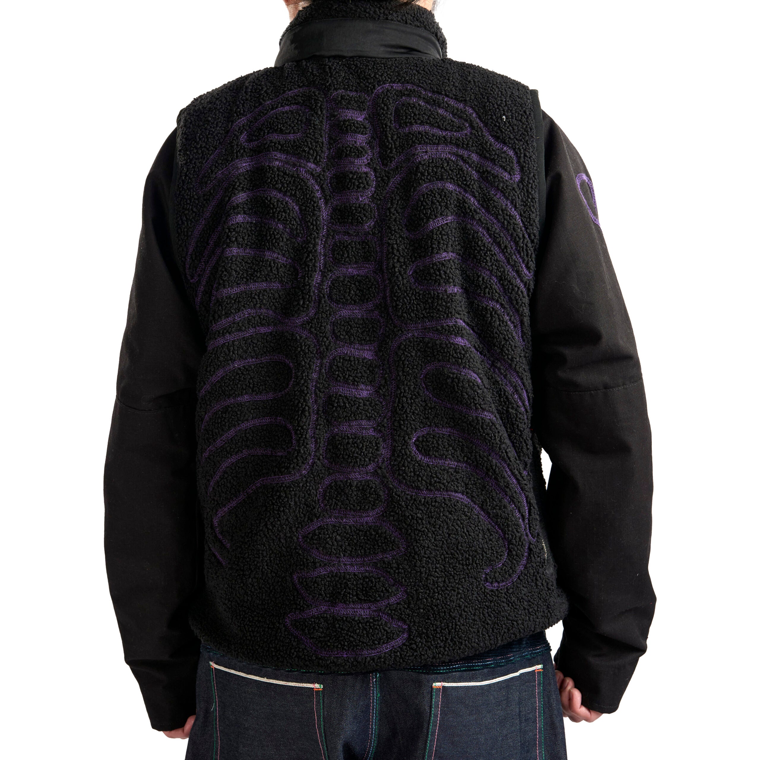 Black fleece vest with purple skeleton design on the back, worn by a person.