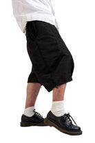 Person wearing black shorts, white socks, and black shoes on a white background