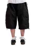 Person wearing black textured shorts on a white background