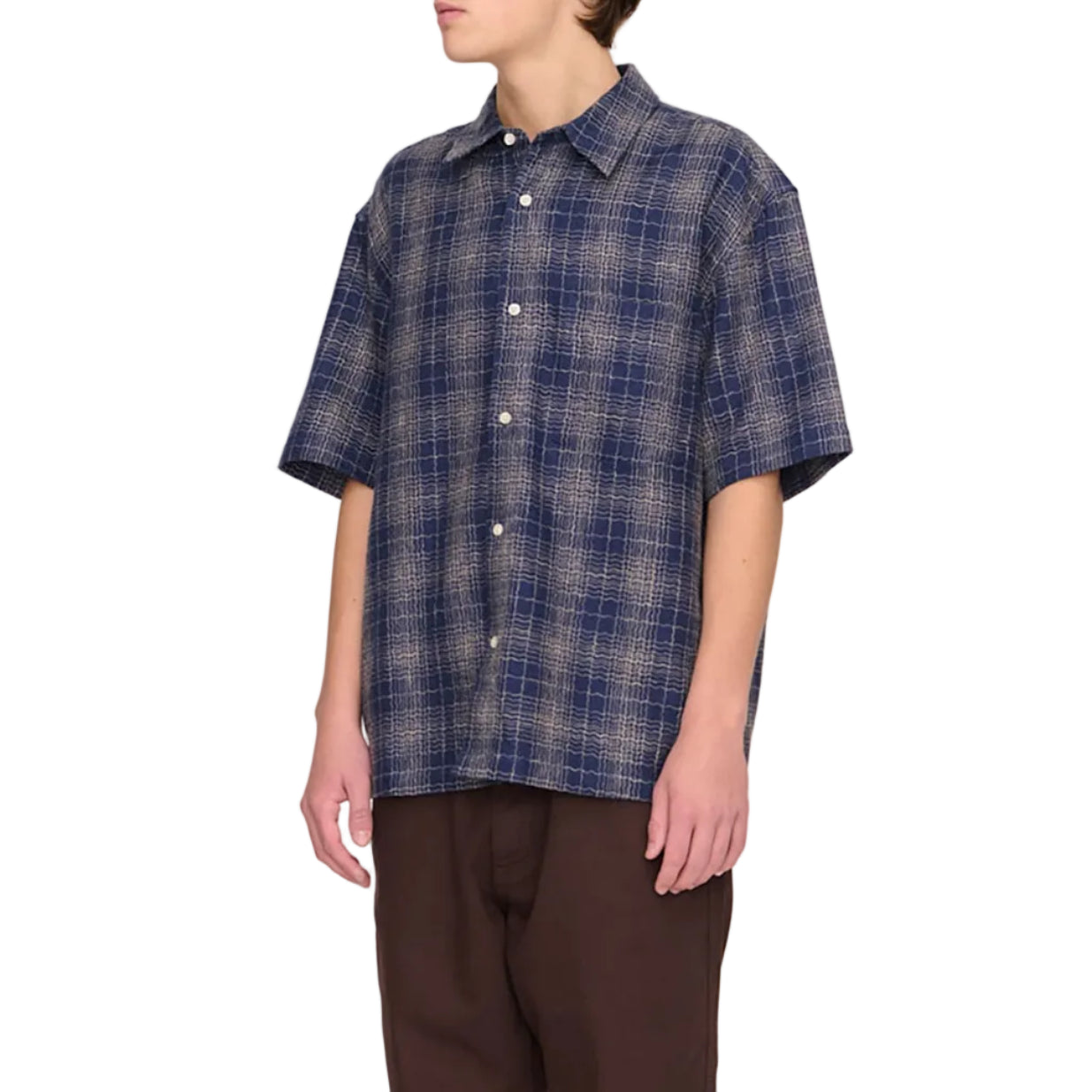 Person wearing a blue plaid shirt and brown pants on a white background
