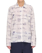 Person wearing a patterned shirt and dark pants on a white background