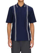 Person wearing a navy polo shirt with white accents and gray pants on a white background