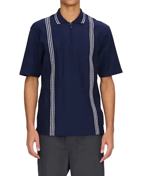 Person wearing a navy polo shirt with white accents and gray pants on a white background