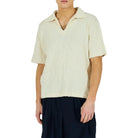 Man wearing a beige shirt and black skirt on a white background