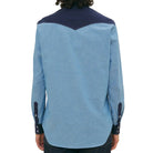 Person wearing a blue shirt with a dark collar and sleeves on a beige background