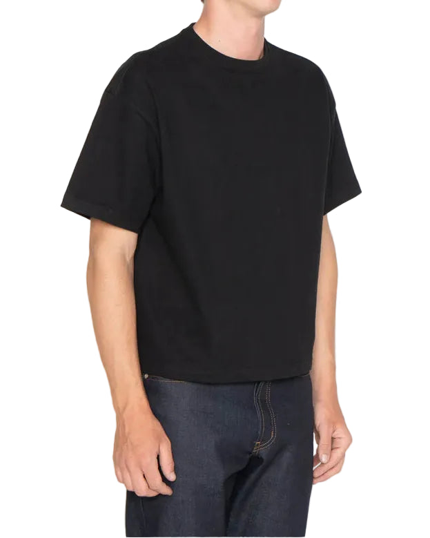 Person wearing a black t-shirt and dark jeans on a white background