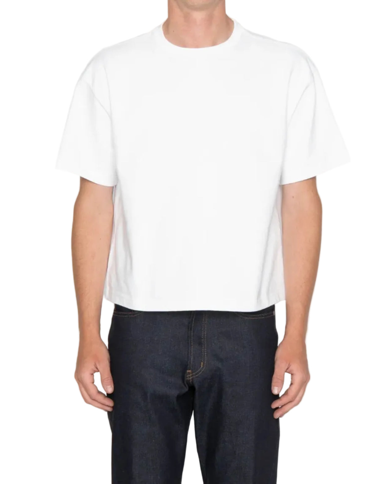 Person wearing a plain white t-shirt and dark jeans on a light gray background