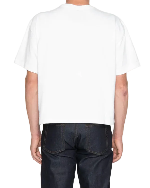 Person wearing a plain white t-shirt and dark jeans on a light gray background