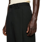 Person wearing black pants on a plain background