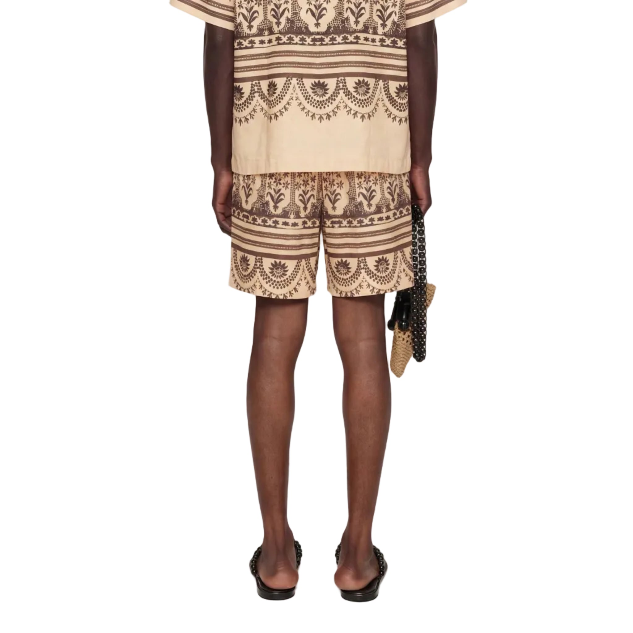 Person wearing a beige and brown patterned outfit on a white background