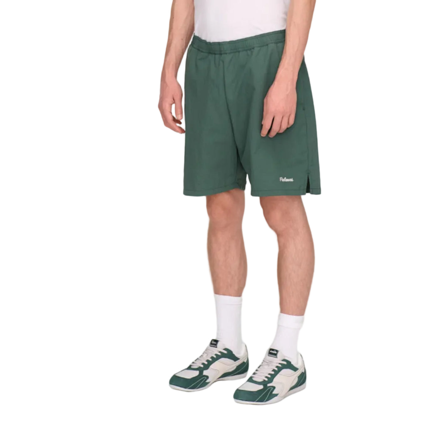 Person wearing a white shirt and green shorts on a plain background