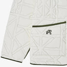 Close-up of a white jacket with geometric pattern and green trim on a white background