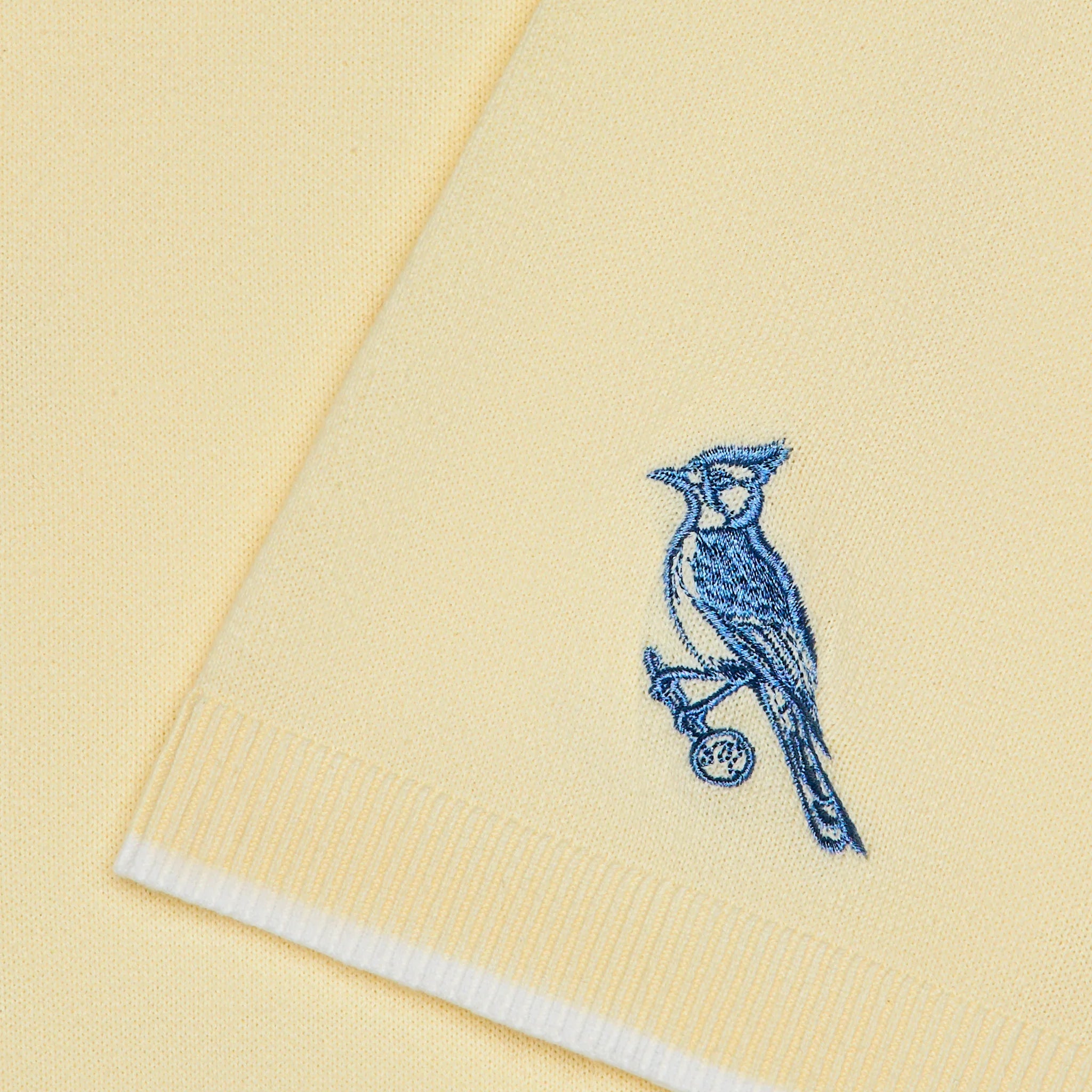 Yellow fabric with a blue bird embroidery on a yellow background
