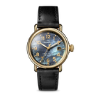 Gold watch with a grey face and black band on a white background