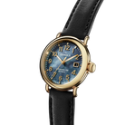 Shinola watch with black leather strap and gold case on white background