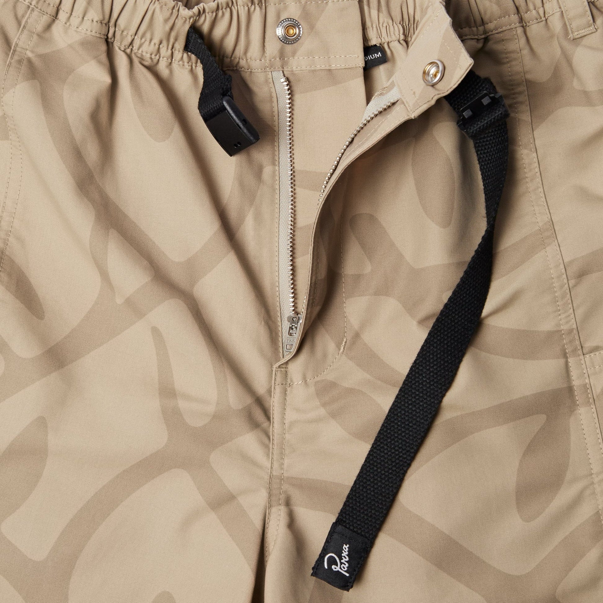 Close-up of beige pants with a zipper and black strap