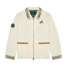 Cream-colored jacket with intricate patterns and branding on a white background