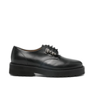 Black leather shoe with decorative brooch on a white background
