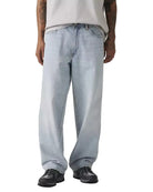Person wearing light blue jeans and black shoes on a white background
