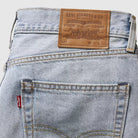 Close-up of Levi's jeans with brand label and pocket detail on a light gray background