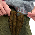 Person adjusting a mesh pocket on a green pair of shorts with a white background