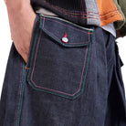 Close-up of a person wearing dark blue denim shorts with a pocket detail on a white background