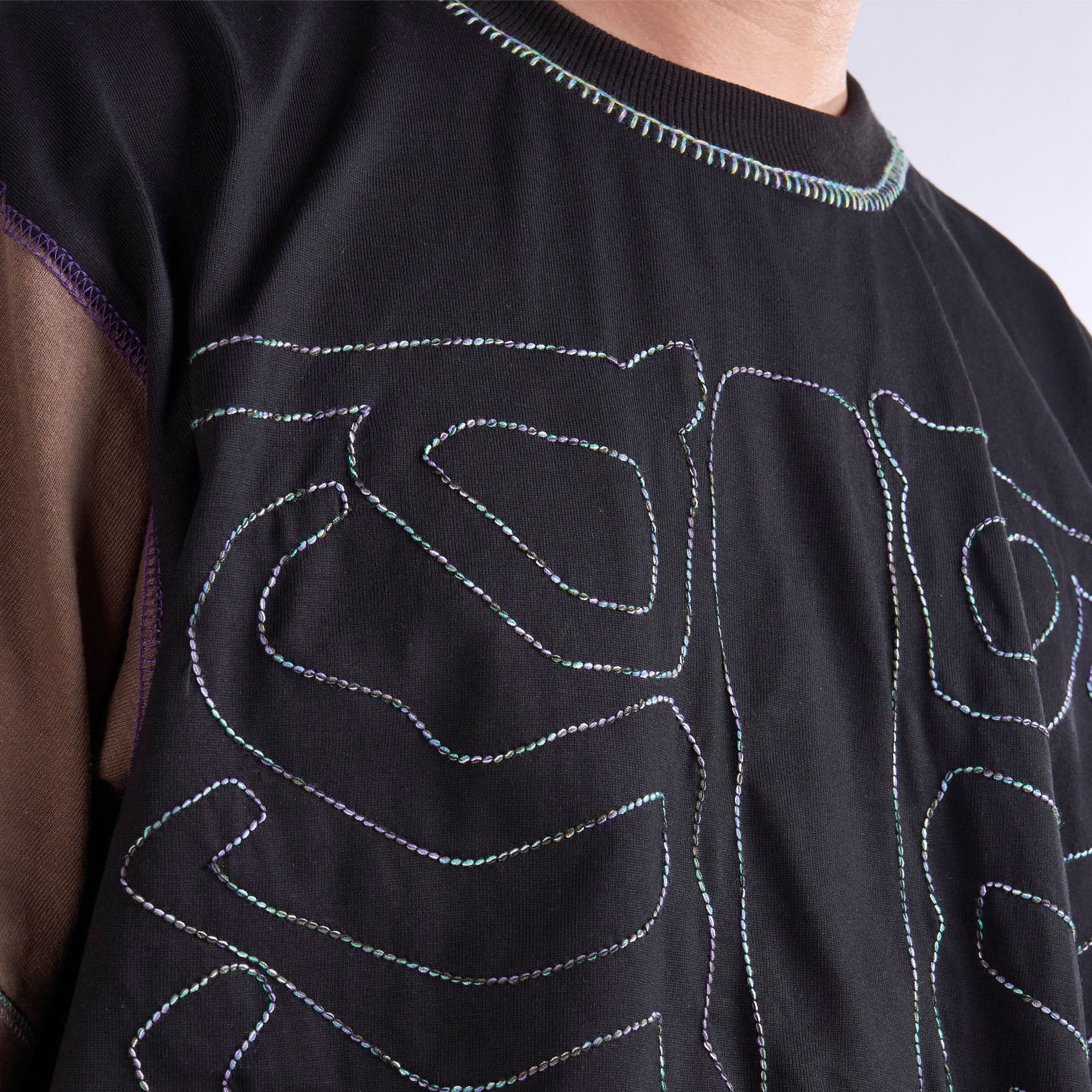 Black garment with colorful stitching details on a plain background