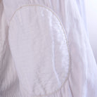 Close-up of a white shirt with an elbow and stitching detail.