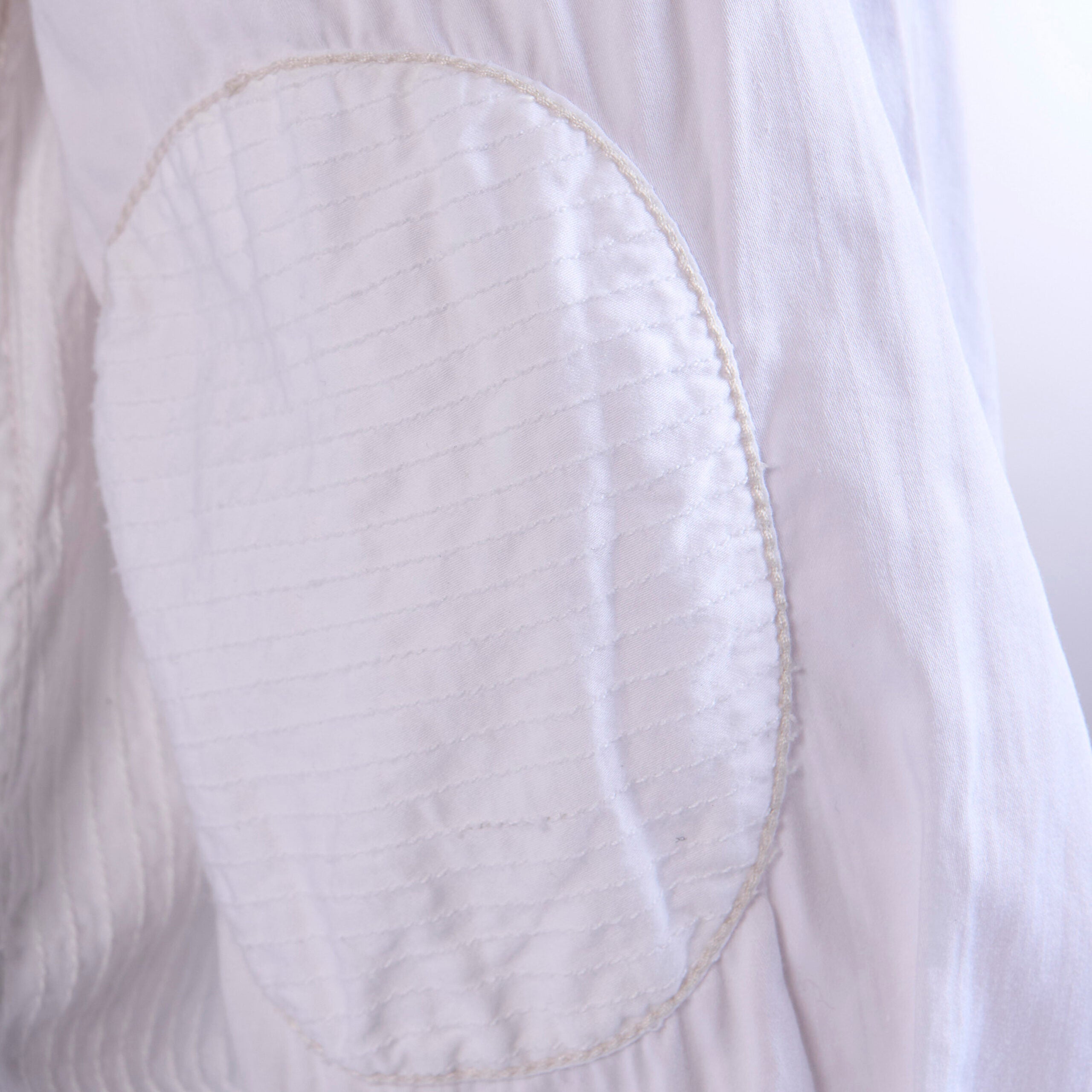 Close-up of a white shirt with an elbow and stitching detail.
