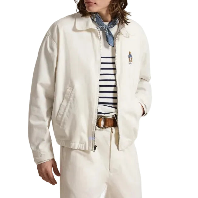 Person wearing a white jacket with an embroidered bear on the chest on a white background