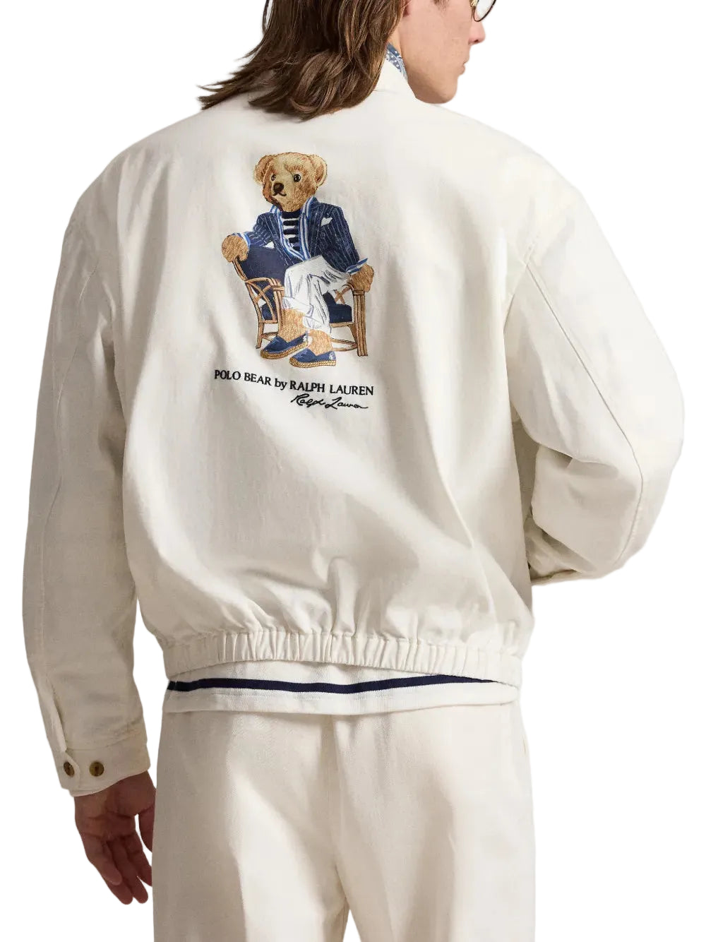 Person wearing a white jacket with a Polo Bear Ralph Lauren logo on the back.