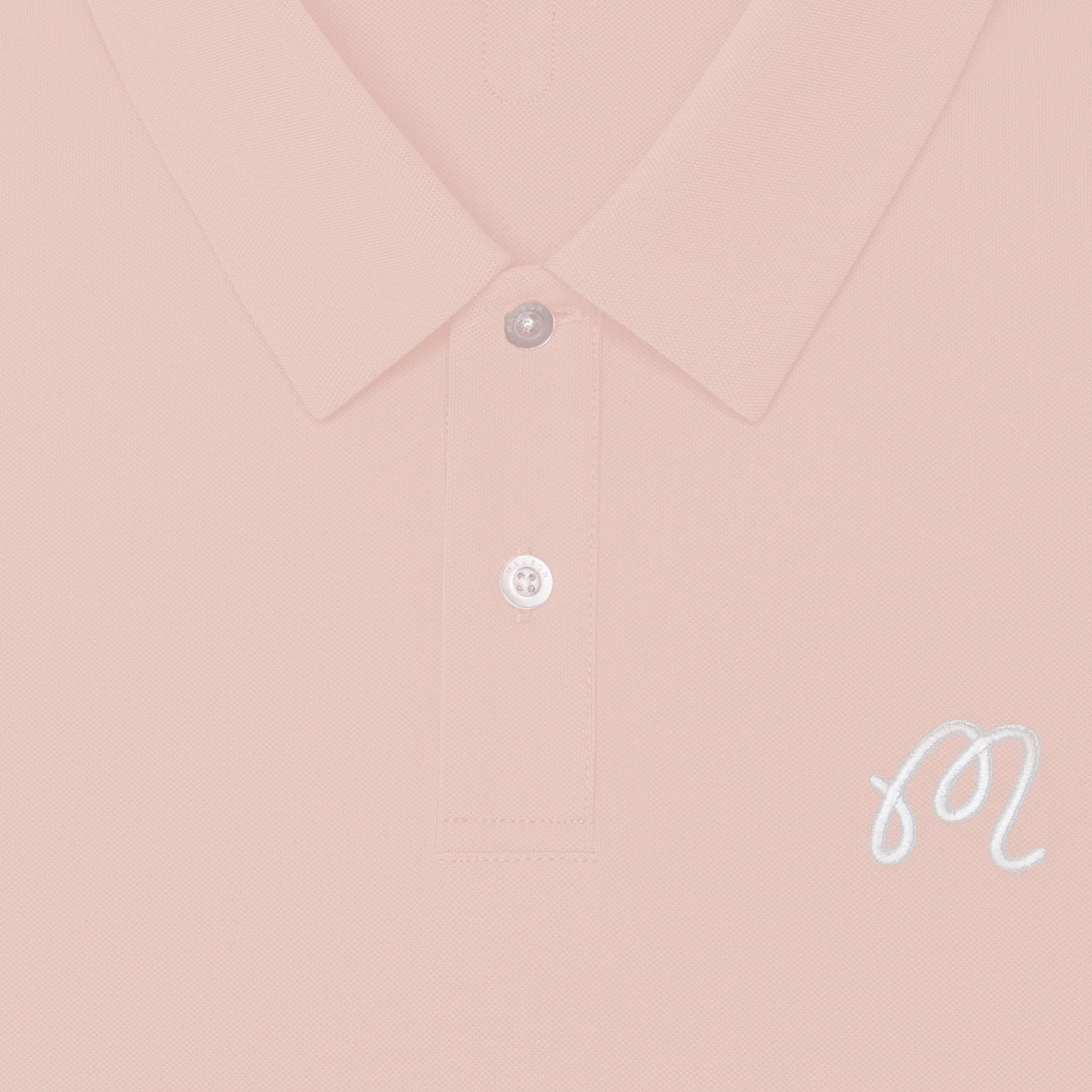 Close-up of a pink polo shirt with an 'M' logo at the chest