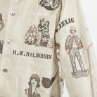 Close-up of a cream-colored button-up shirt featuring vintage-style illustrated prints and text including 'H.W. MILBOURN'