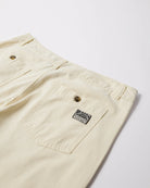 Close-up of a pair of off-white work pants showing the waistband, pocket, and a black and white 'Parra' brand patch on the pocket.