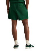 Person wearing green shorts and white socks with dark shoes on a white background