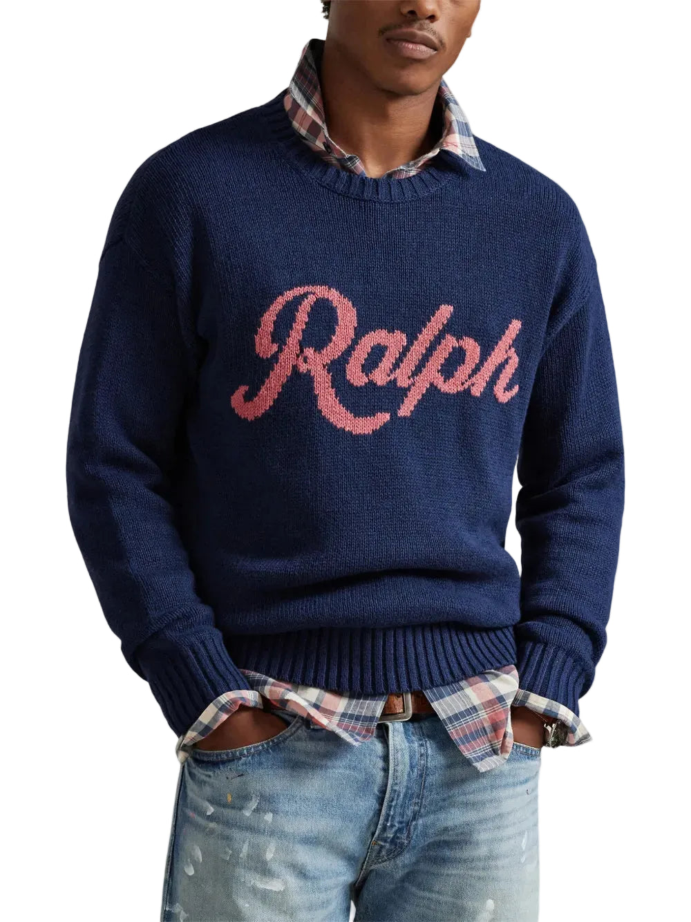 Man wearing a navy sweater with 'Ralph' text, plaid shirt, and jeans on a white background