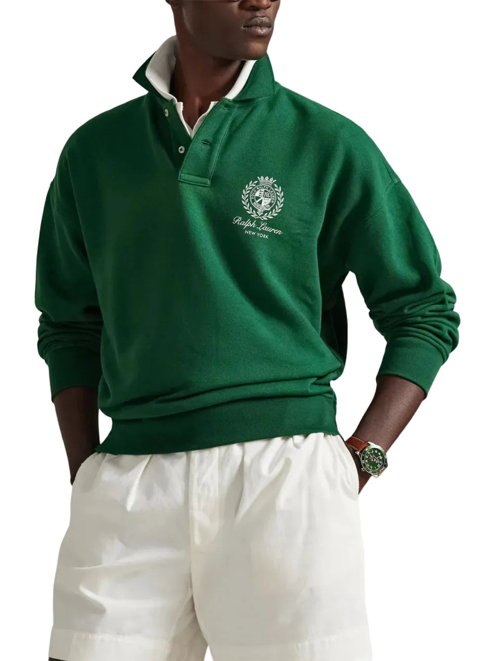 Person wearing a green sweater with a logo, standing against a white background