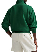 Person wearing a green jacket and white shorts on a plain background